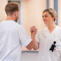 En mannlig og en kvinnelig sykepleier gir hverandre high five