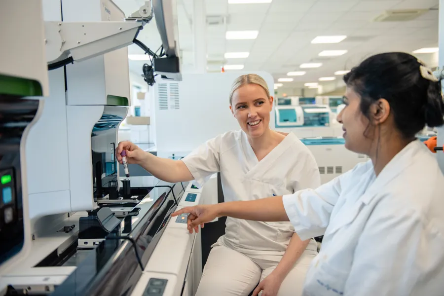 En kvinne som viser en mann noe på datamaskinen