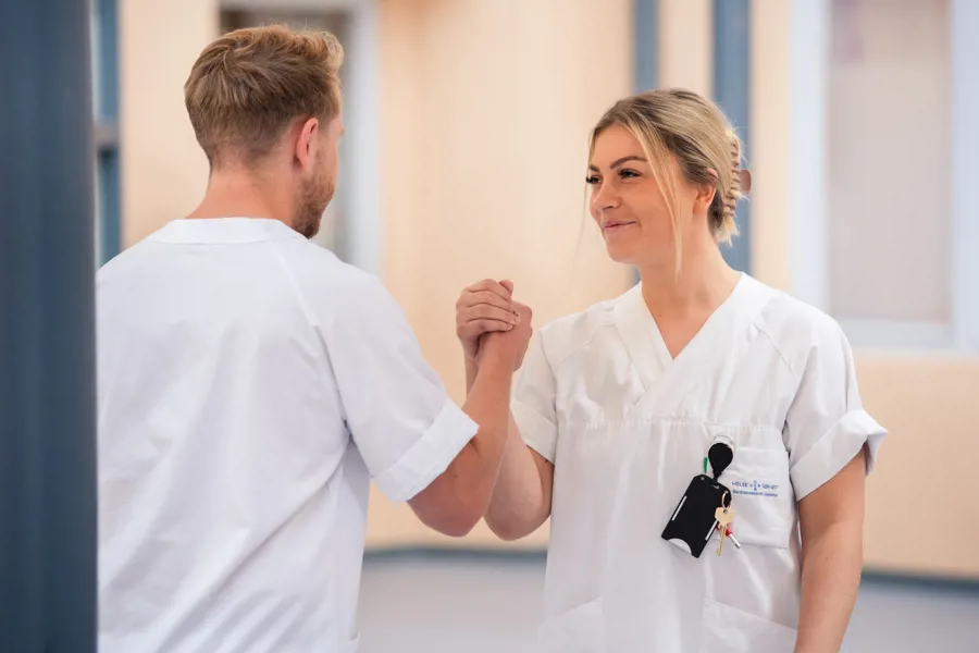 En mannlig og en kvinnelig sykepleier gir hverandre high five