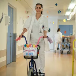 En person i hvit frakk som skyver en barnevogn med en kurv med blomster