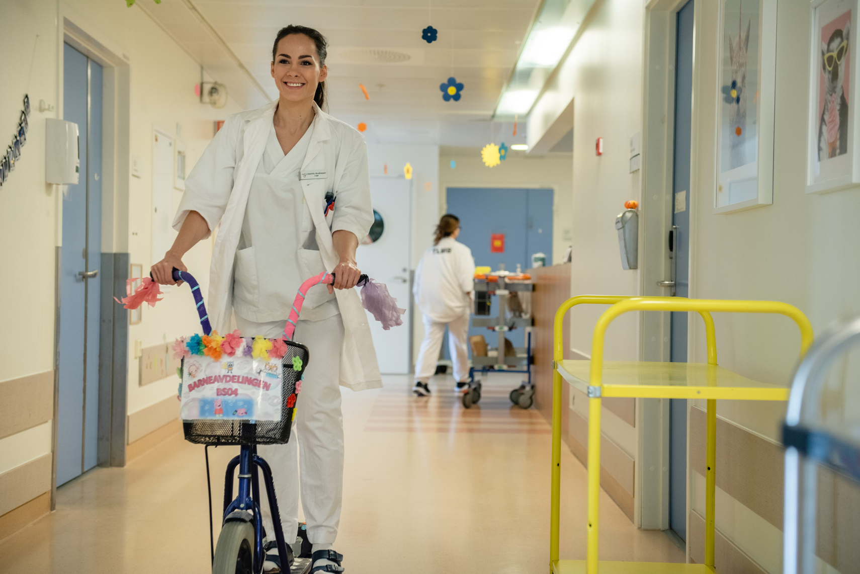 En person i hvit frakk som skyver en barnevogn med en kurv med blomster