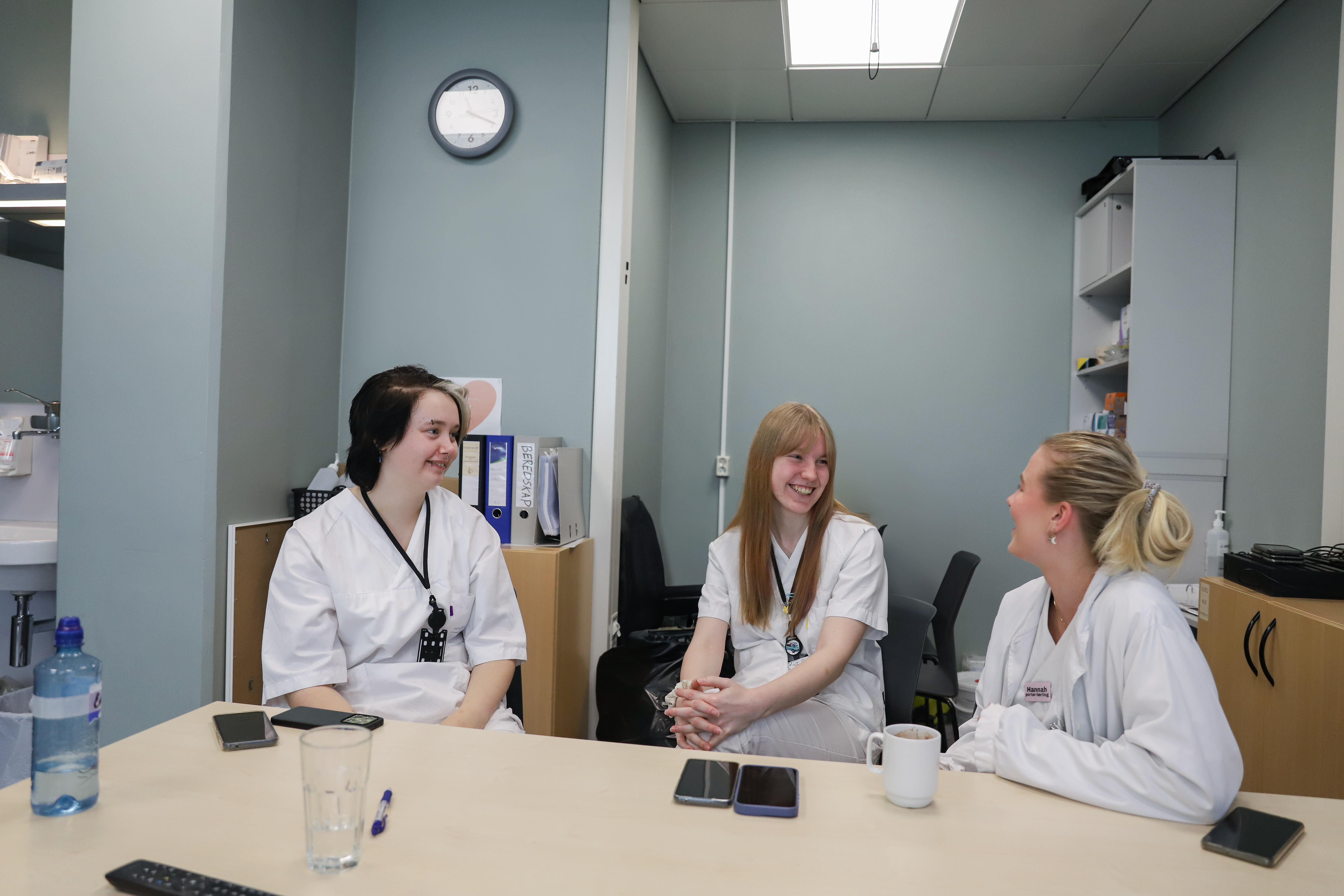 tre mennesker sitter ved et bord og prater