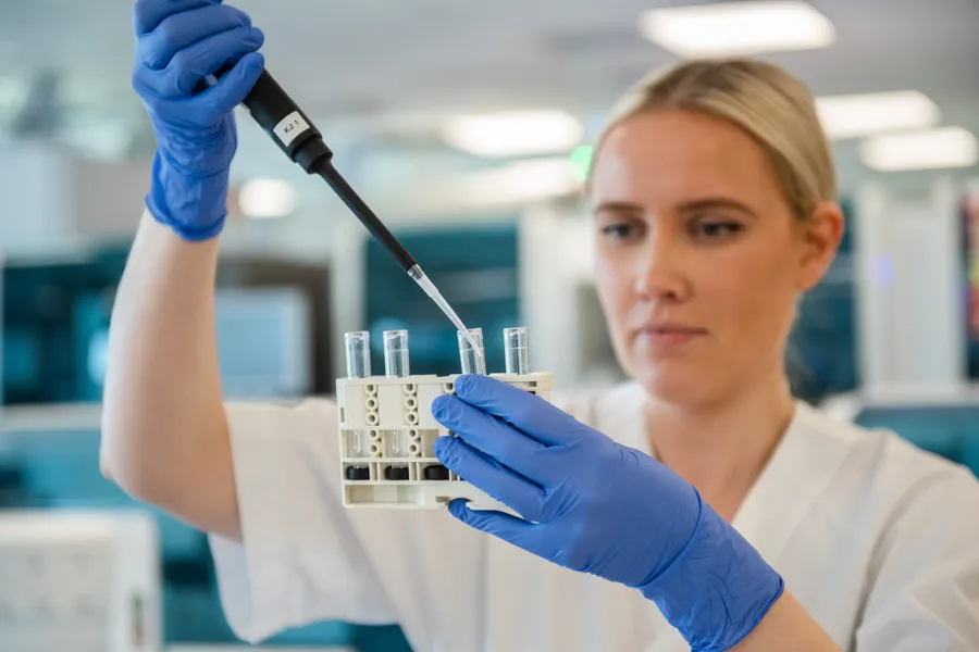 En person i en laboratoriefrakk som holder en sprøyte