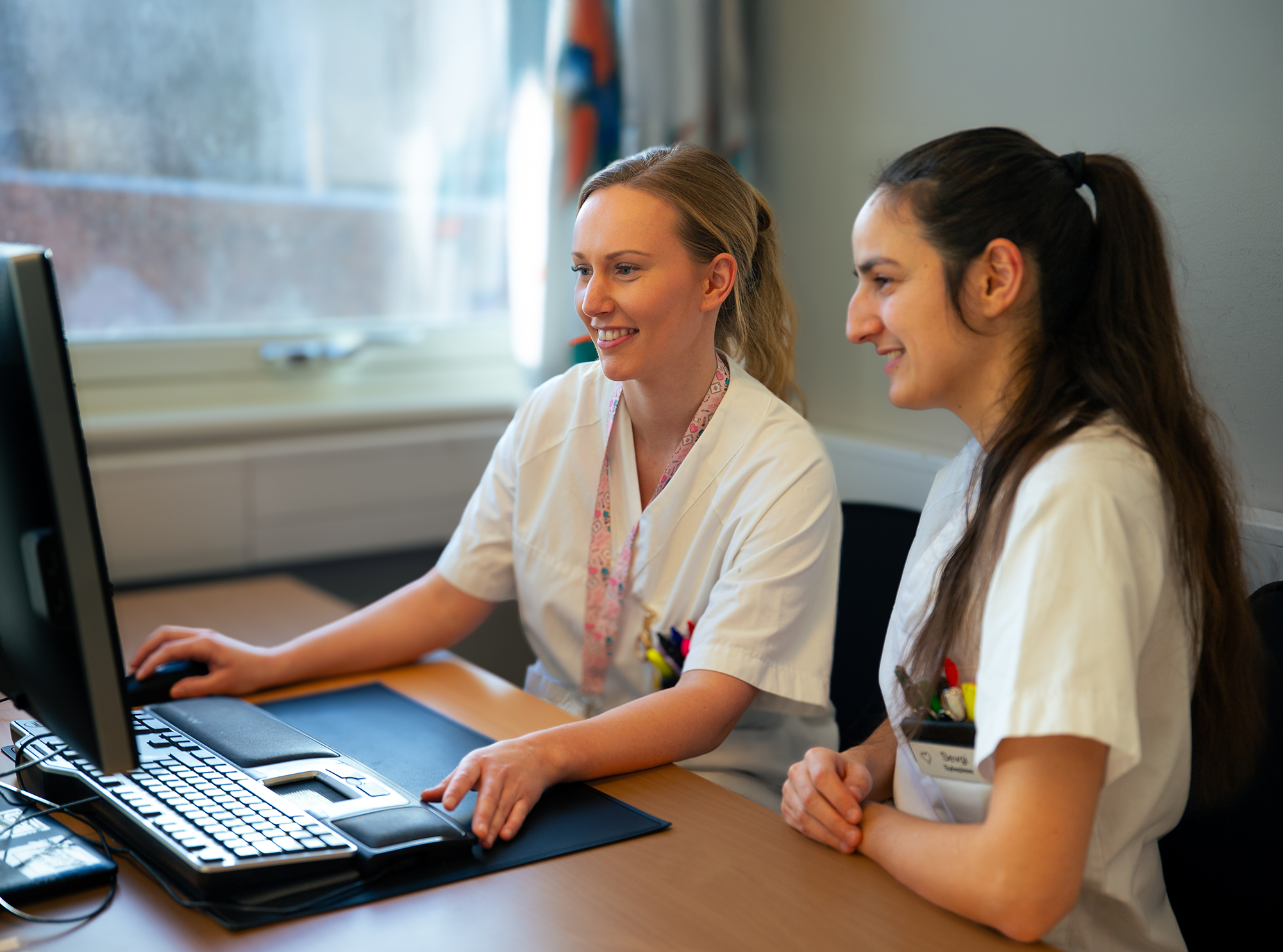 Kvinner i hvite skjorter som ser på en dataskjerm
