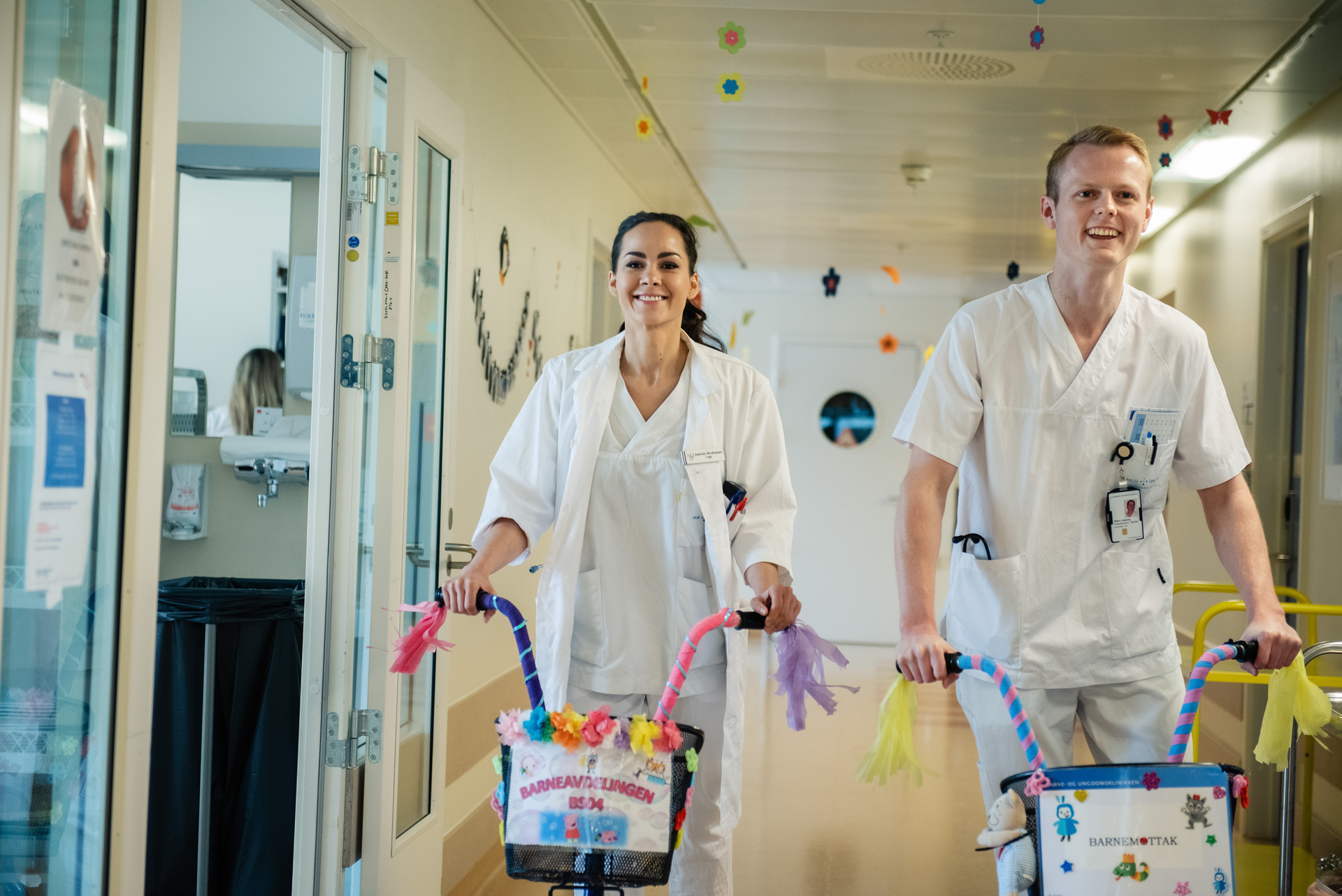 En mann og kvinne på sparkesykler i en sykehusgang