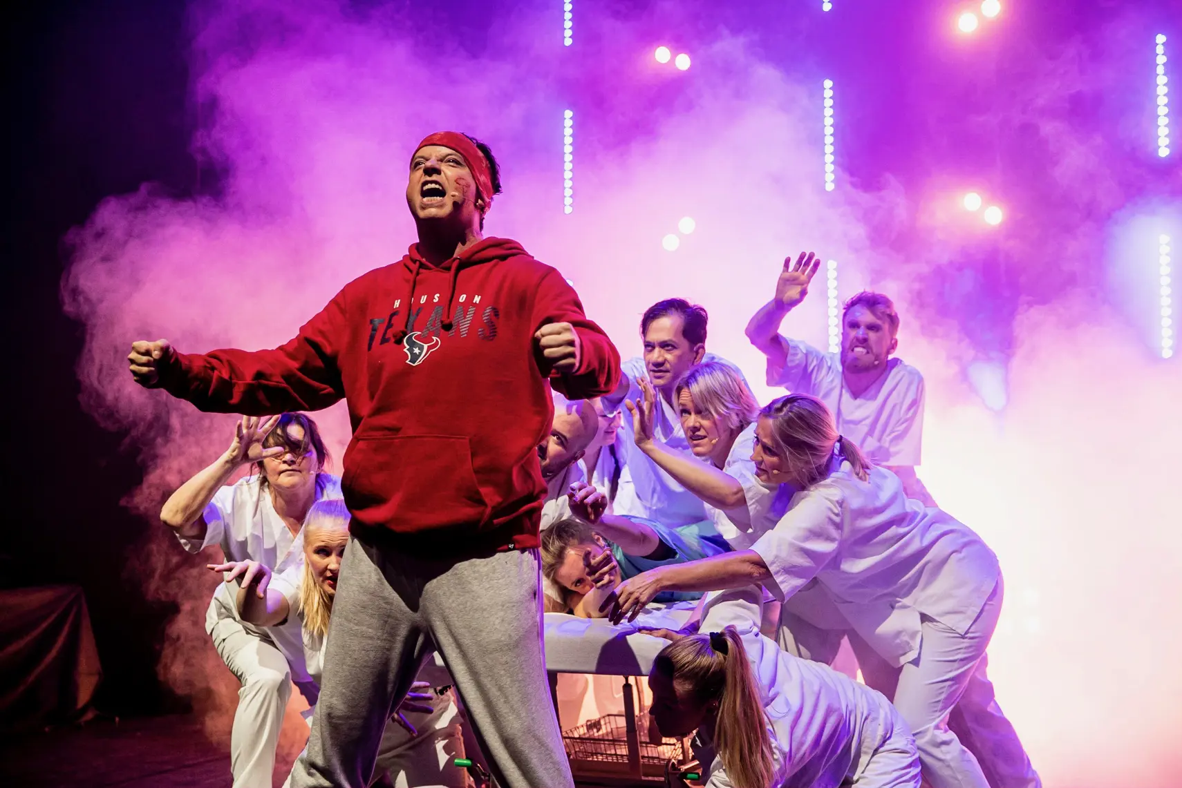 En mann som står på en scene med en gruppe mennesker rundt seg