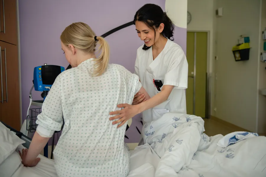 En sykepleier som hjelper pasient i sengen