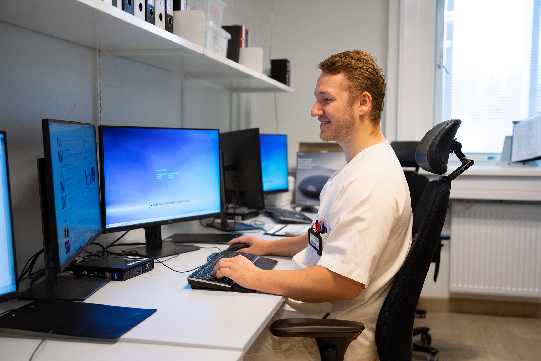 En sykepleier som sitter ved et skrivebord med en datamaskin