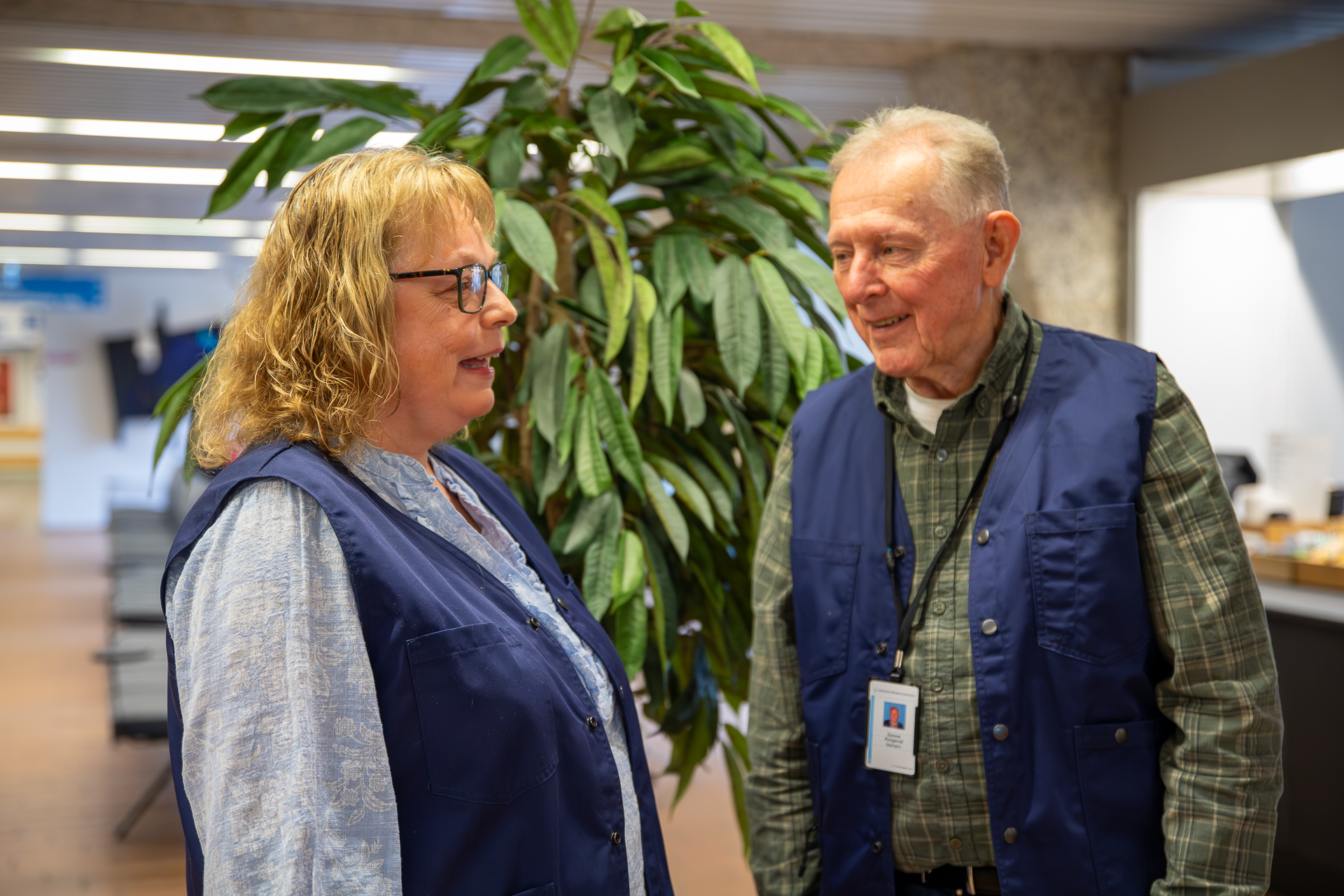 A man and a woman standing next to a plant