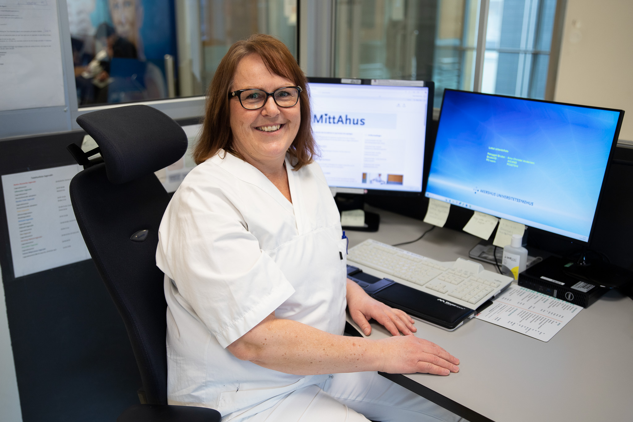 En person som sitter ved et skrivebord med datamaskin og papirer