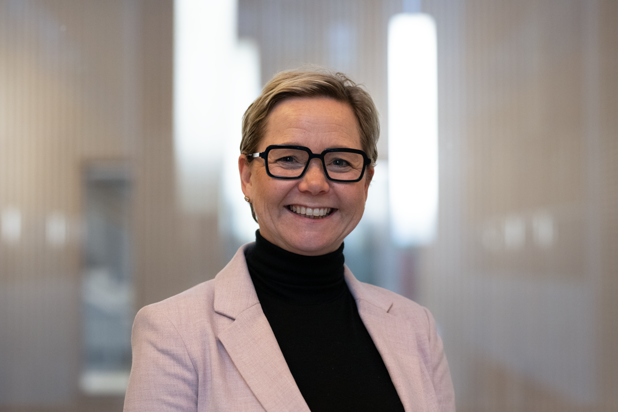 Portrett av smilende kvinne i lys rosa dressjakke