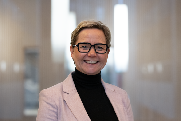 Portrett av smilende kvinne i lys rosa dressjakke
