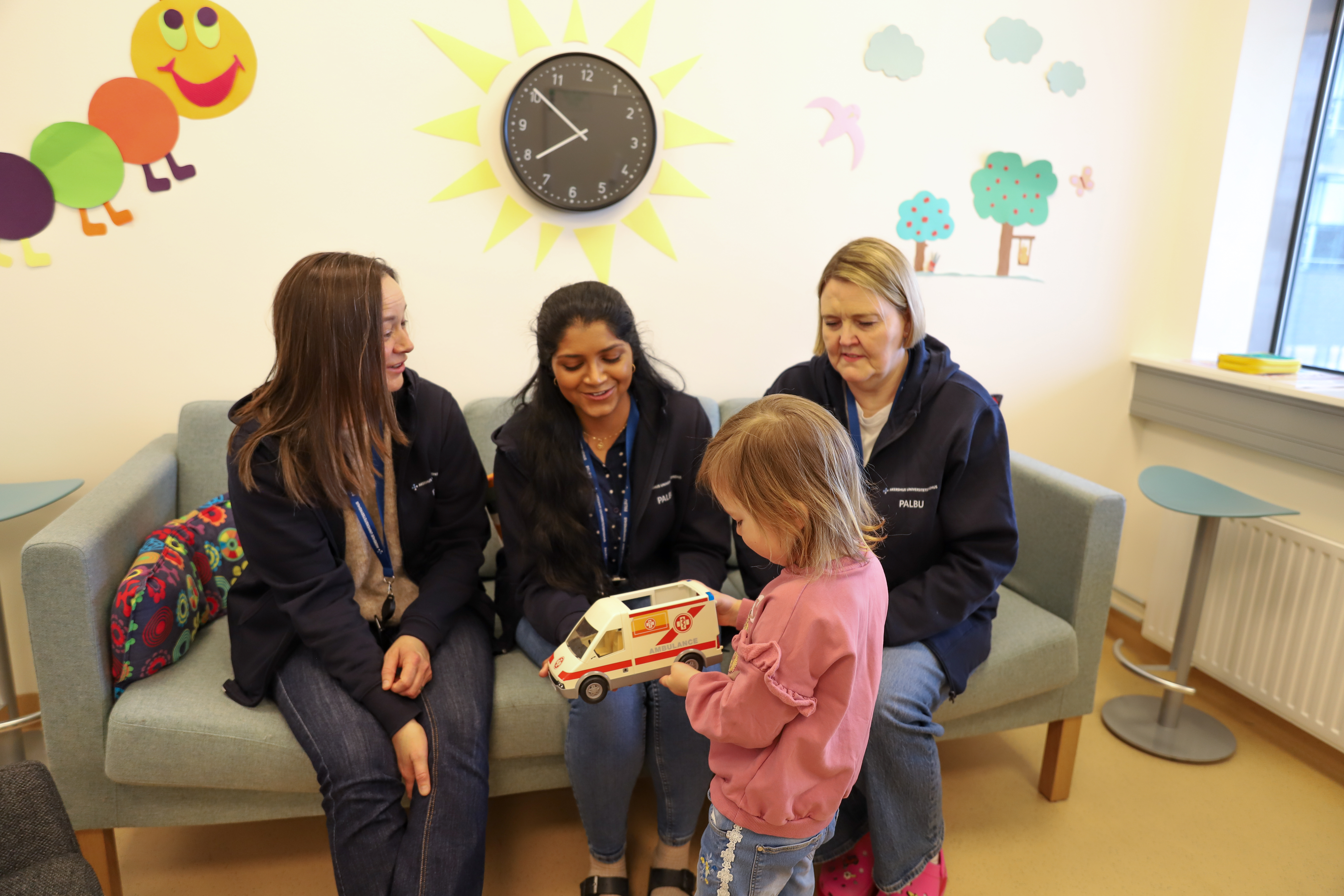 ansatte sitter i sofa barn leker foran