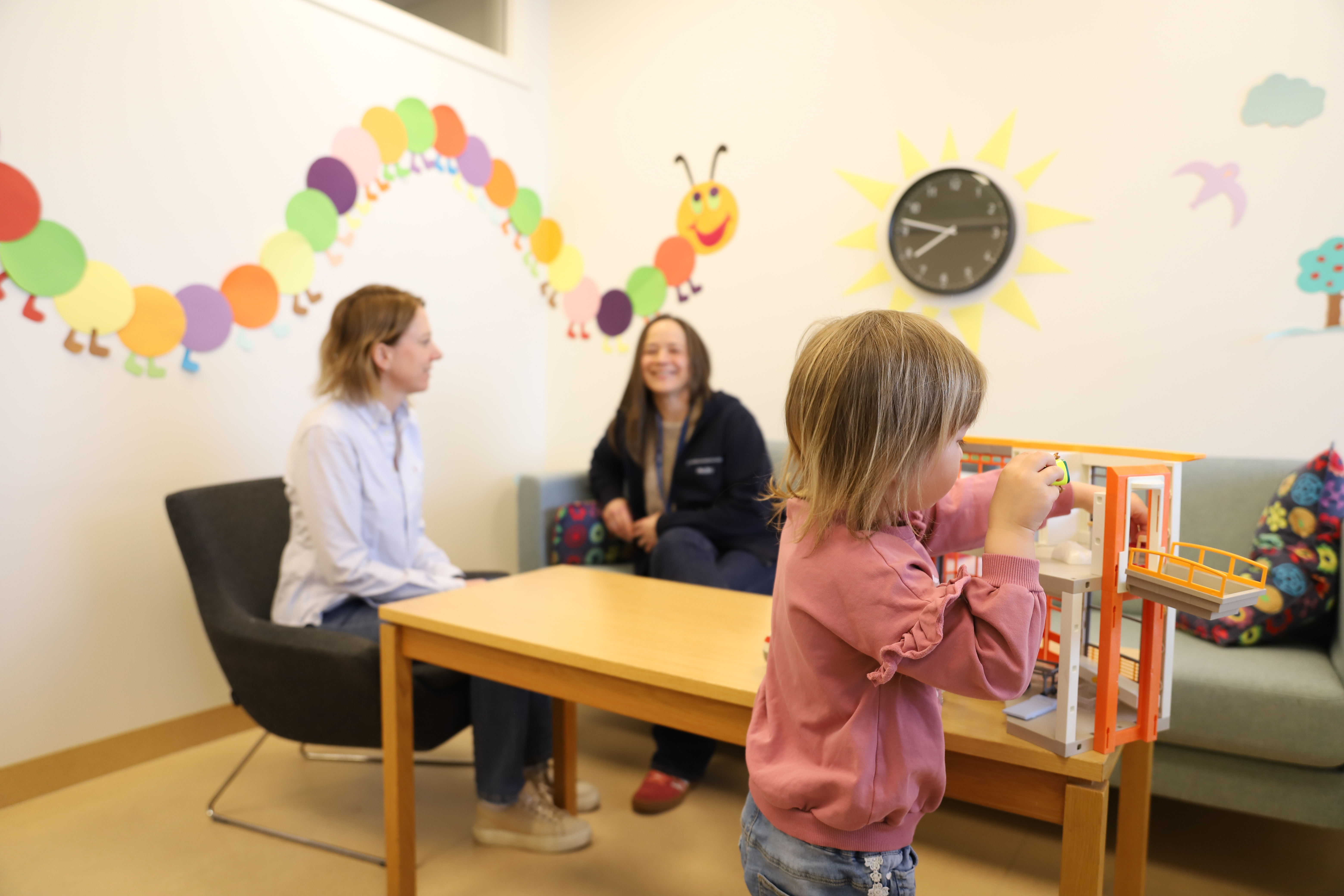 ansatt og pårørende i samtale, barn i forgrunn