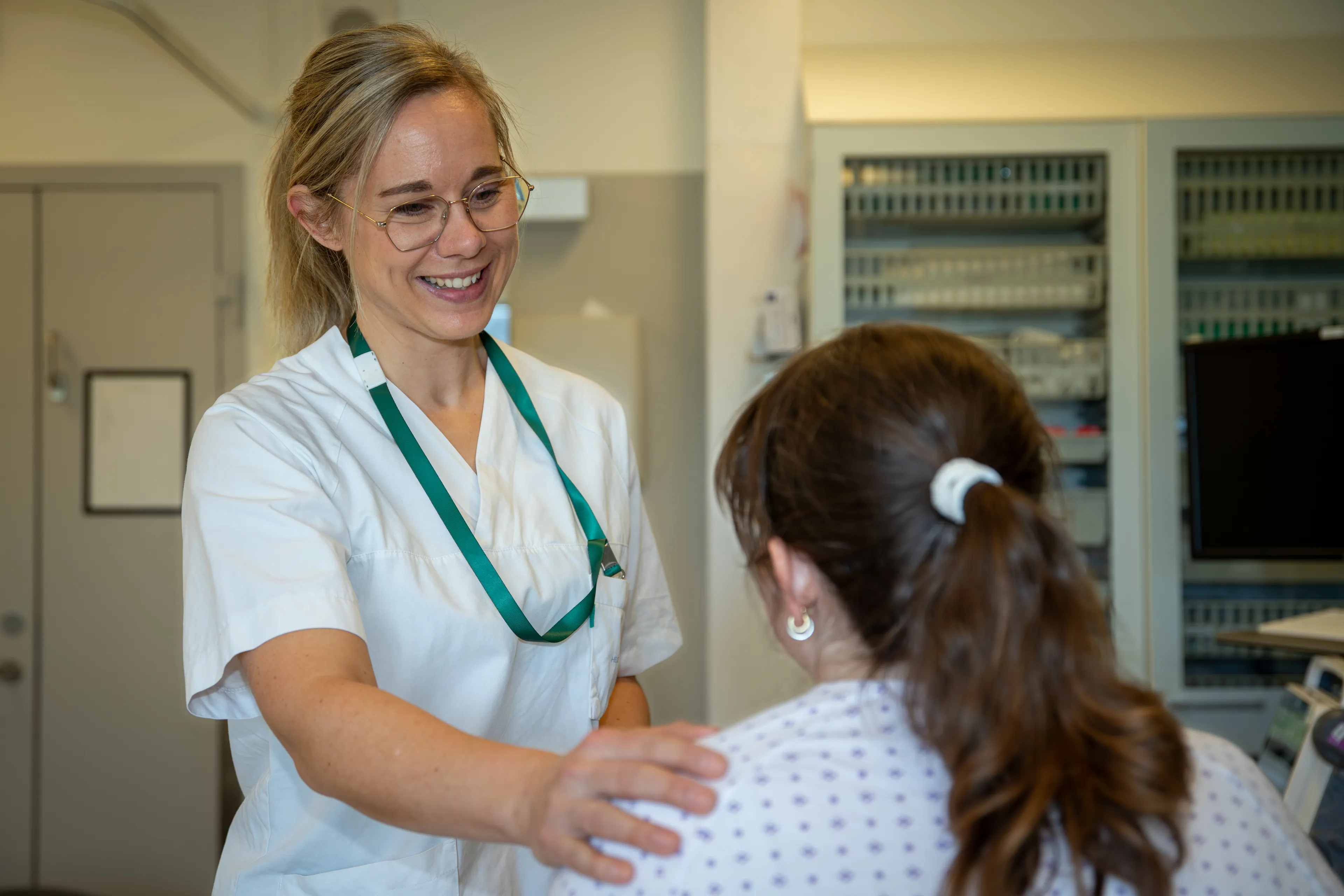 Jordmor som holder hånden på skulderen til pasient som sitter nede.