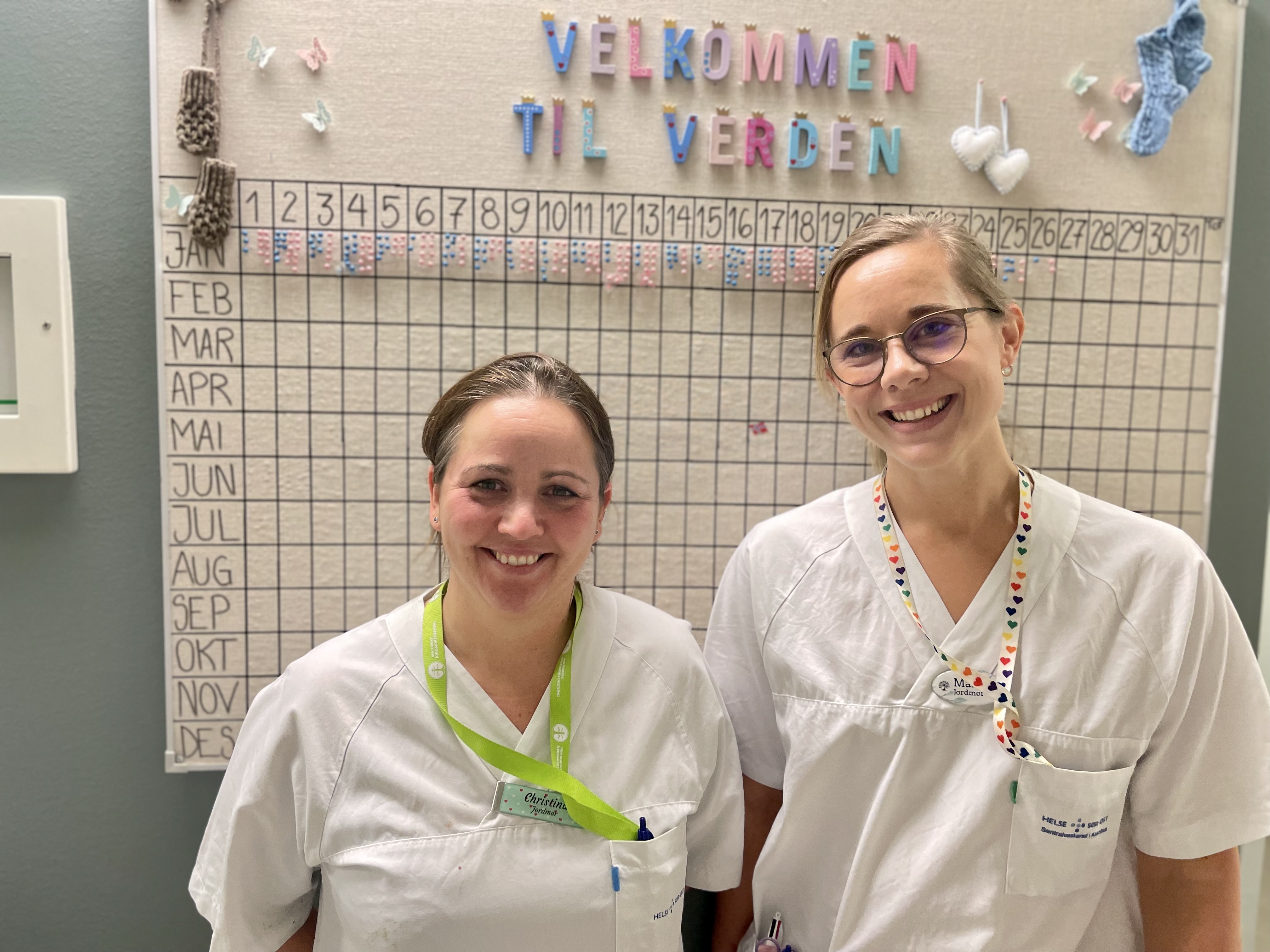 Et par kvinner iført hvite skjorter og smilende til kameraet