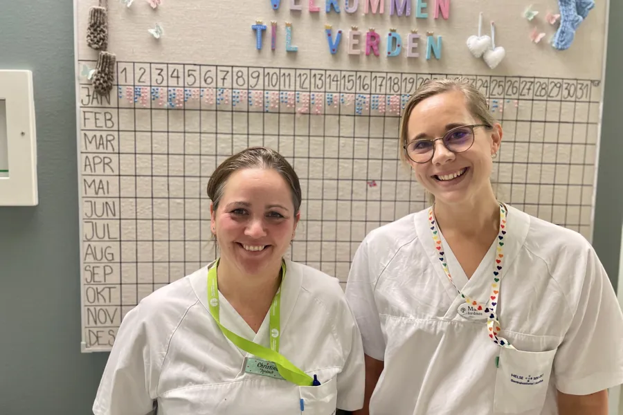 Et par kvinner iført hvite skjorter og smilende til kameraet