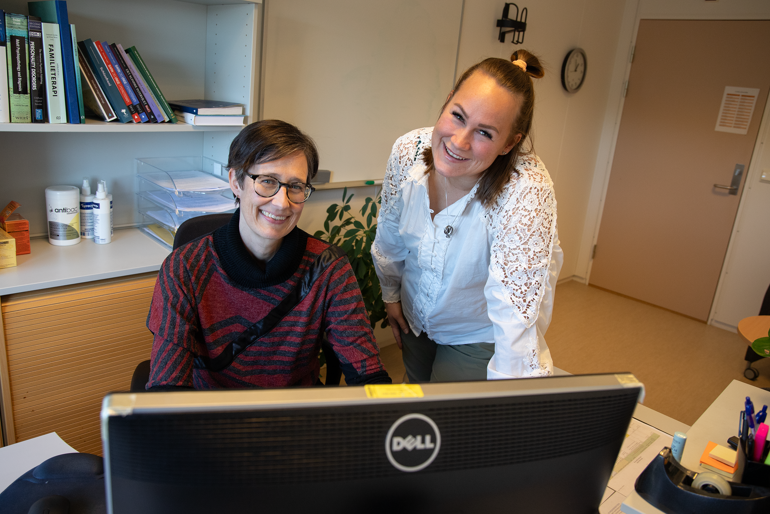 To damer smiler foran pc-skjerm