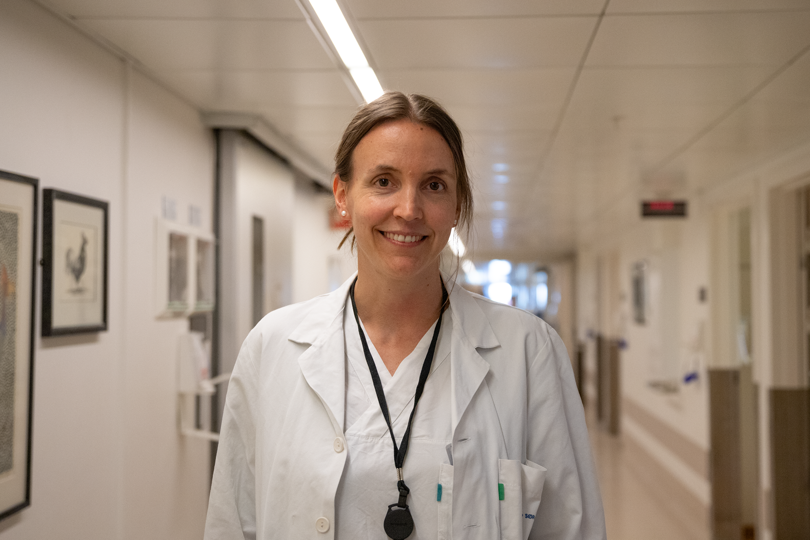 Lege i hvitt tøy smiler mot kamera