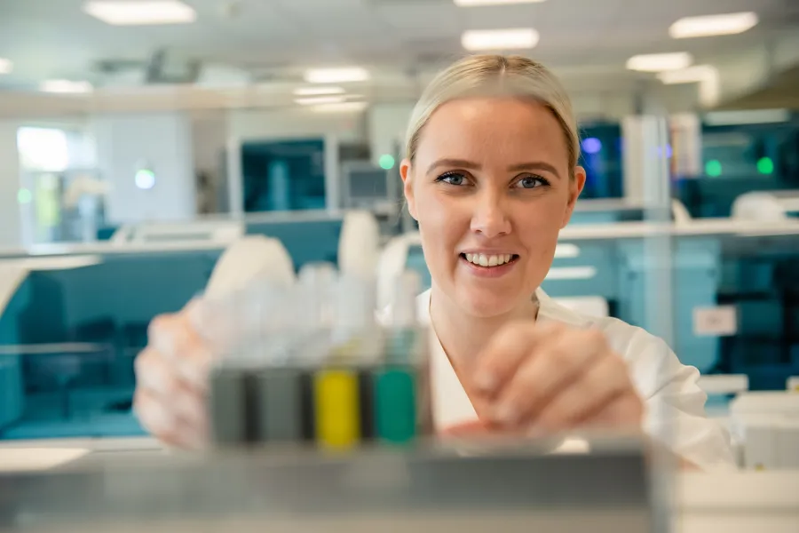 En person som smiler og holder et stykke papir