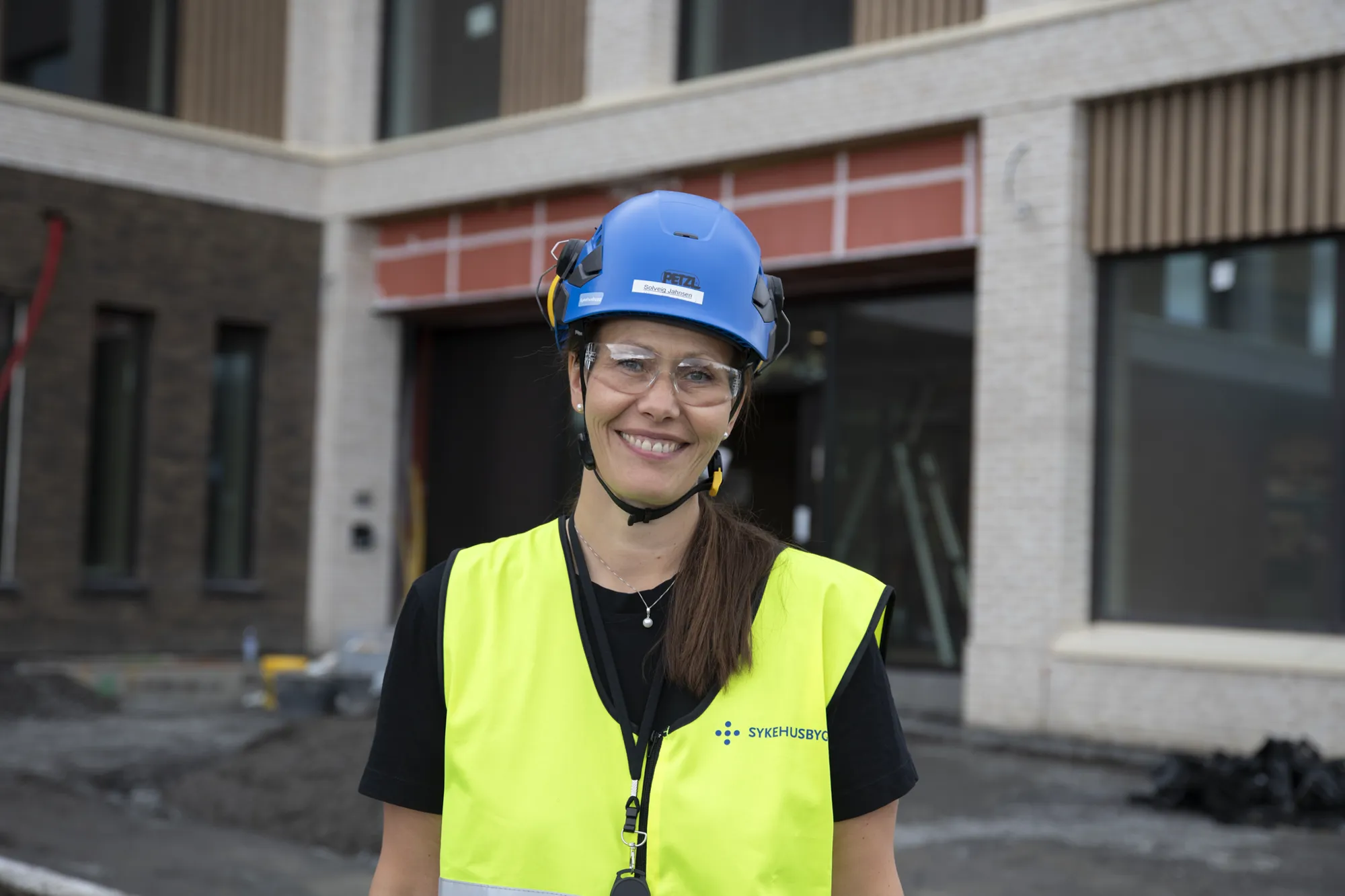 En dame som bruker hjelm utenfor byggeplass