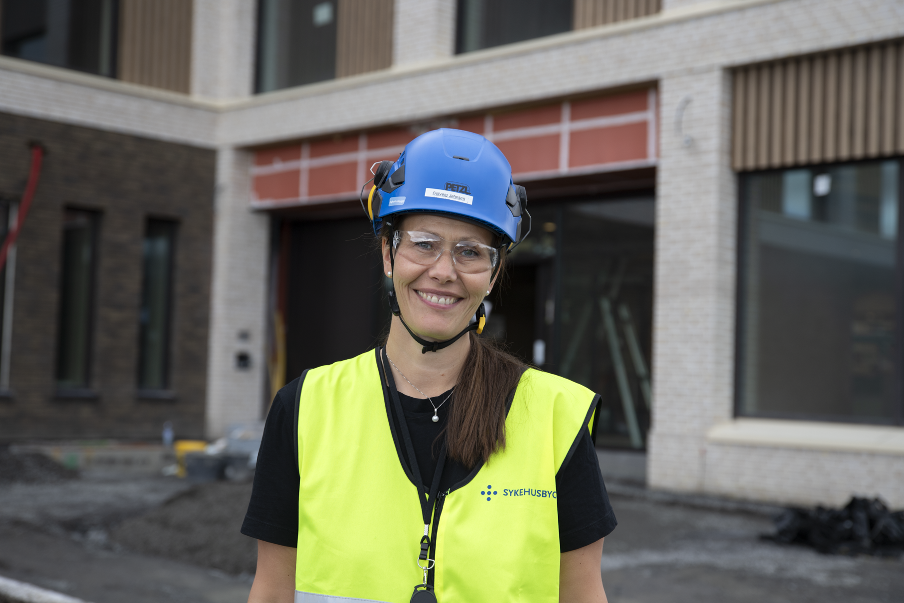 En dame som bruker hjelm utenfor byggeplass