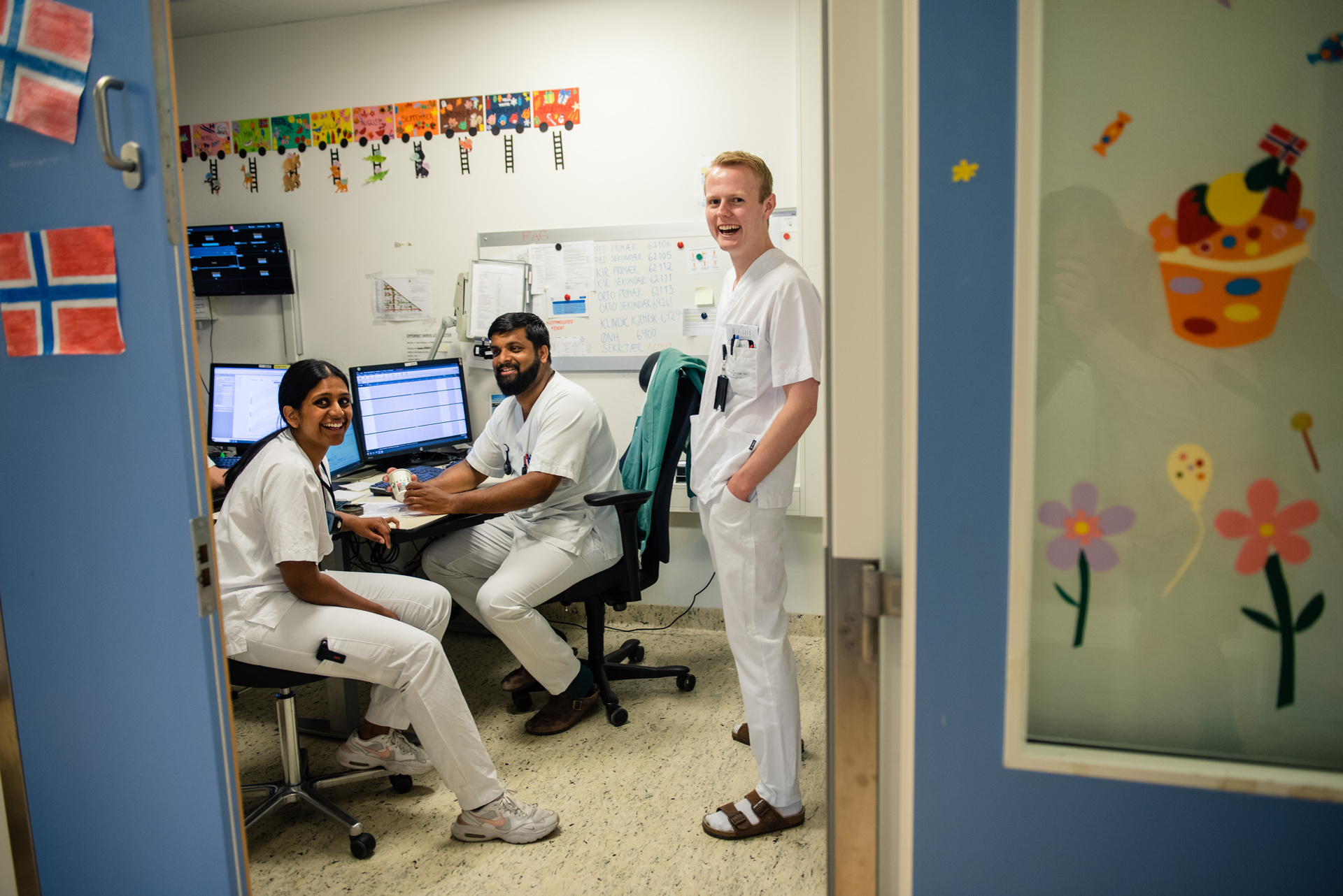 En mann som står ved siden av en mann som sitter i en stol med en datamaskin