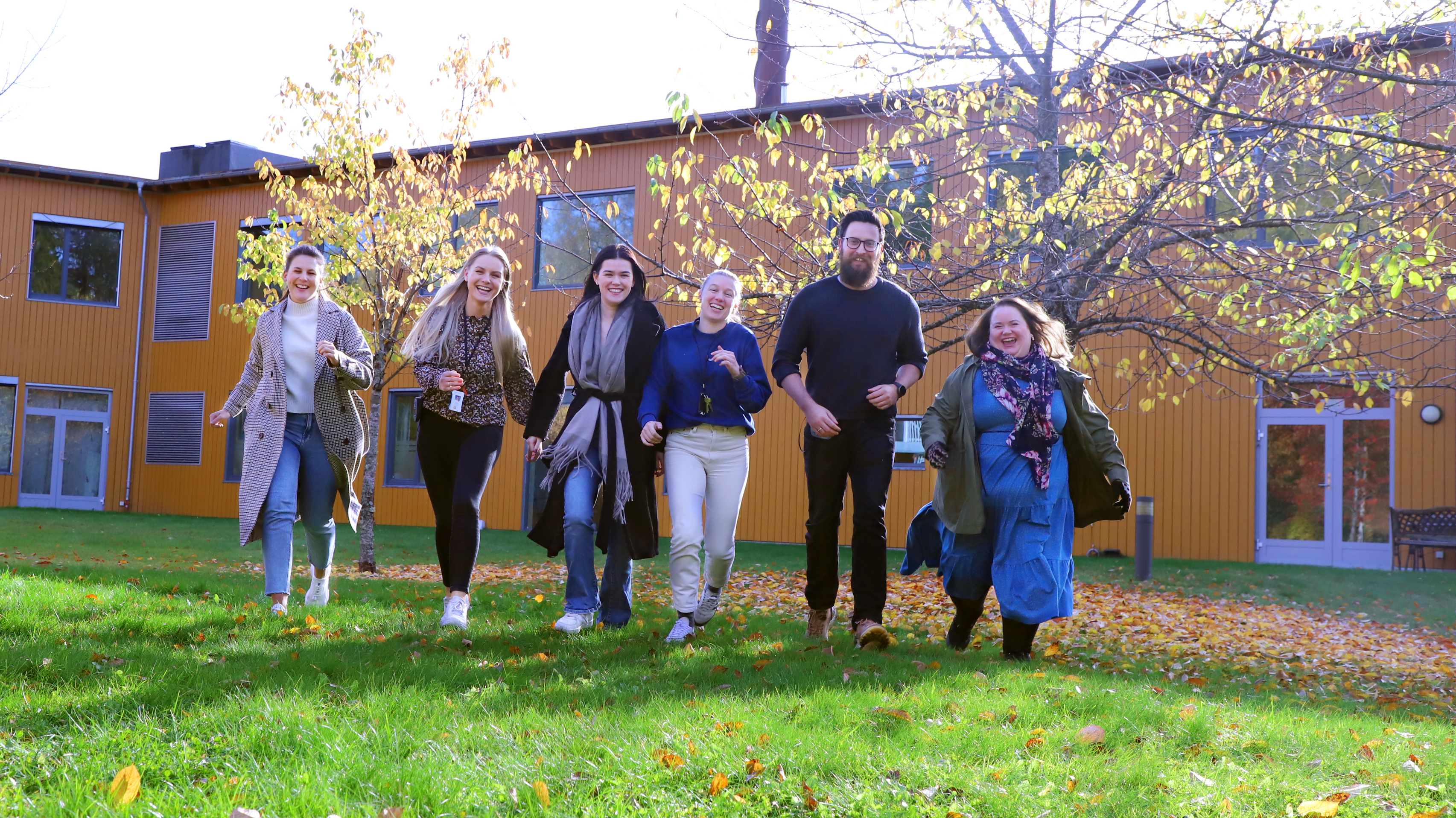 En gruppe mennesker løper smilende mot kamera