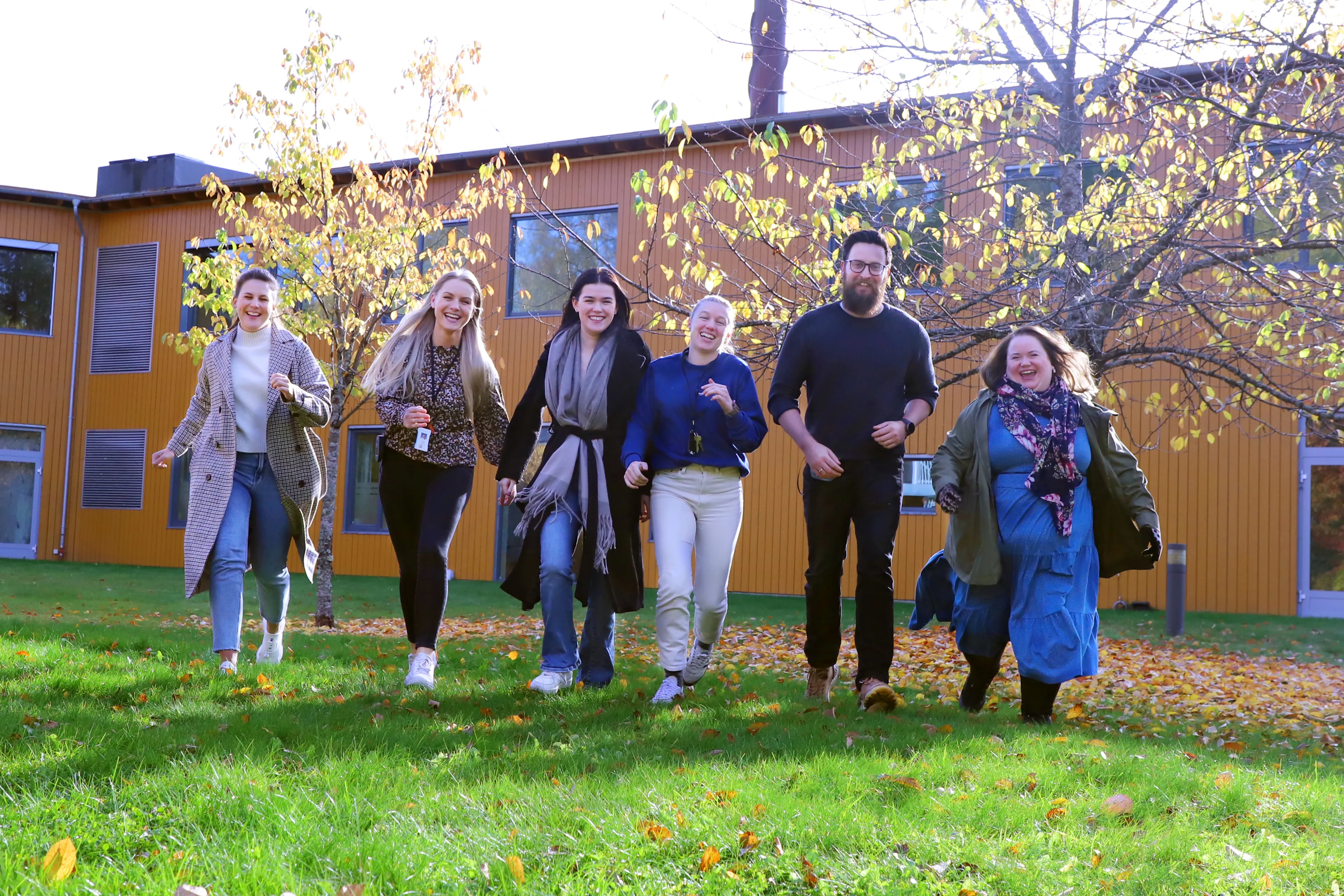 En gruppe mennesker løper smilende mot kamera