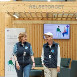 En kvinne og en mann i blå vester ser på hverandre