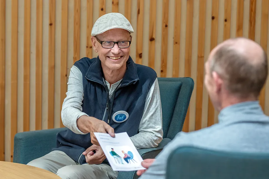 En person som smiler og sitter ved siden av en annen mann
