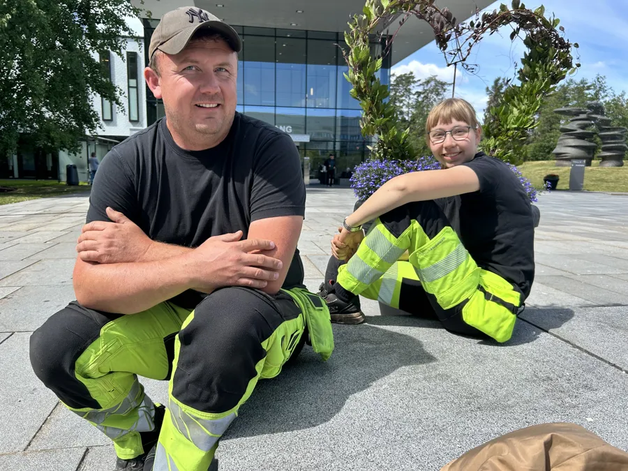 Bilde av Marie Klerud og Kim Lund som sitter ved de blomstrende hjertene ved Barnesenteret og hovedinngangen