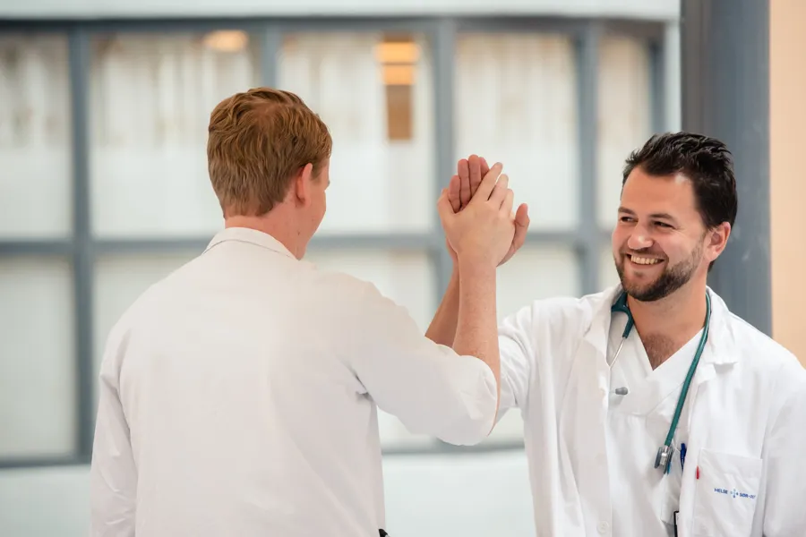 En lege som viser en mann noe på telefonen