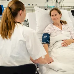 En person i en sykehusseng med en person i en sykehuskjole