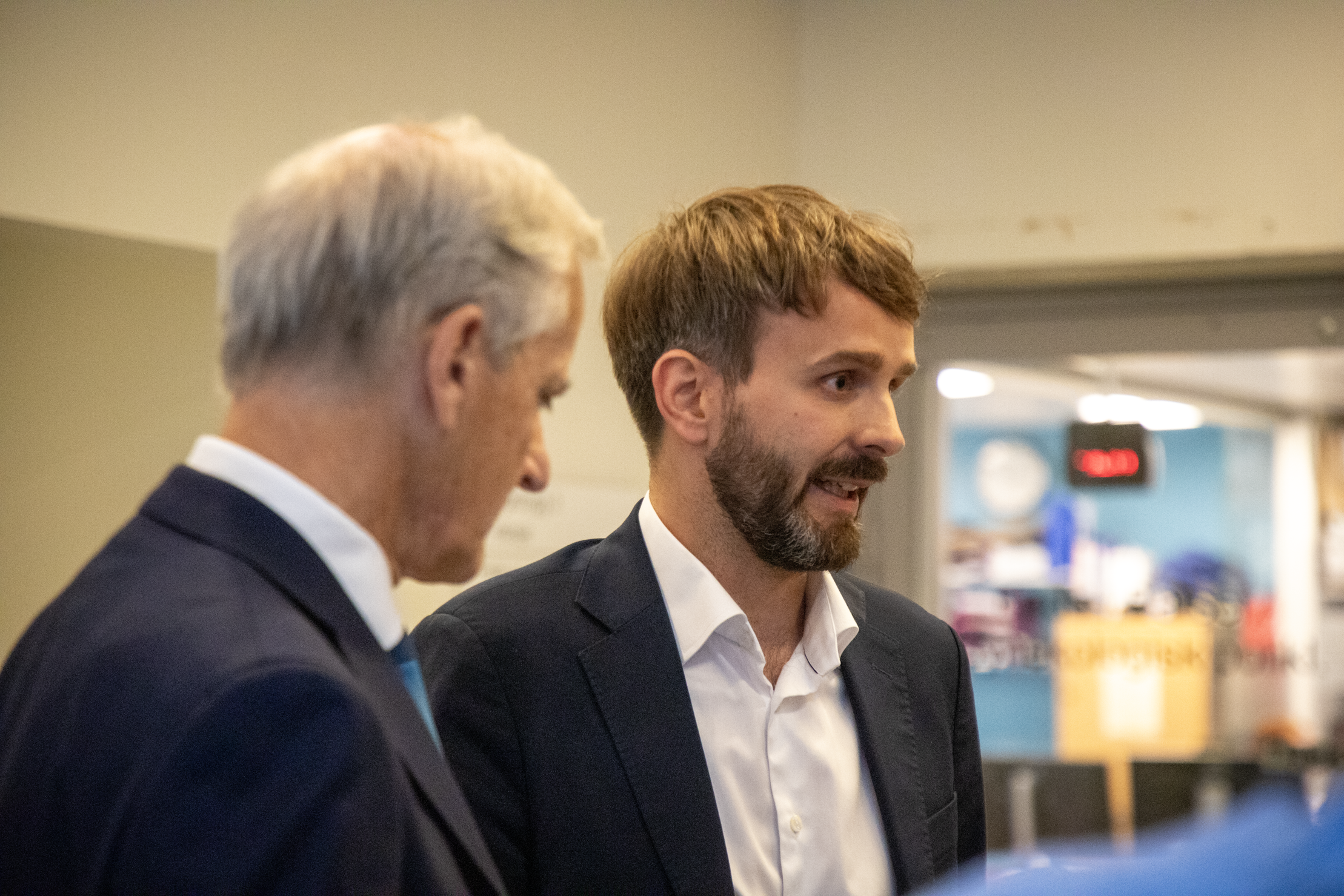 Menn i dress snakker i sykehuskorridor