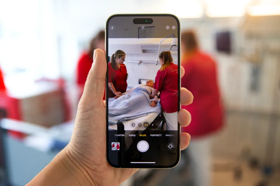 en person tar bilder av to helsepersonell og en pasient med mobilen