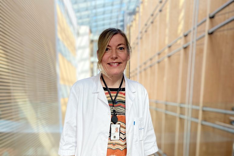 Dame i legefrakk smiler mot kamera