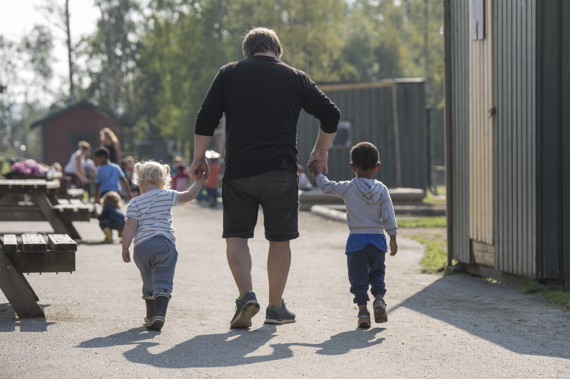 En person og to barn som går