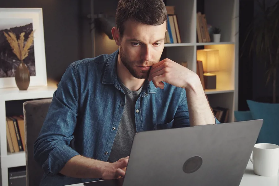 Mann ser konsentrert på en laptop