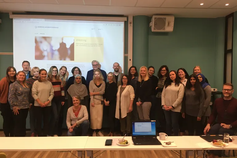 En gruppe mennesker som poserer for et bilde foran en projektorskjerm