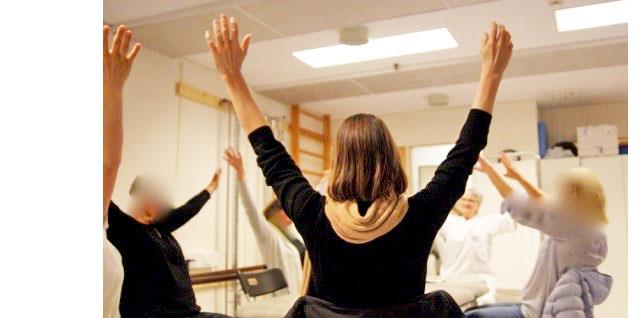 Gruppe med mennesker som sitter i ring med armene opp i været