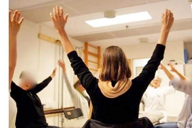 Gruppe med mennesker som sitter i ring med armene opp i været