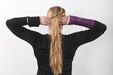 Kvinne står med ryggen til og armen opp, med hendene hvilende på bakhodet