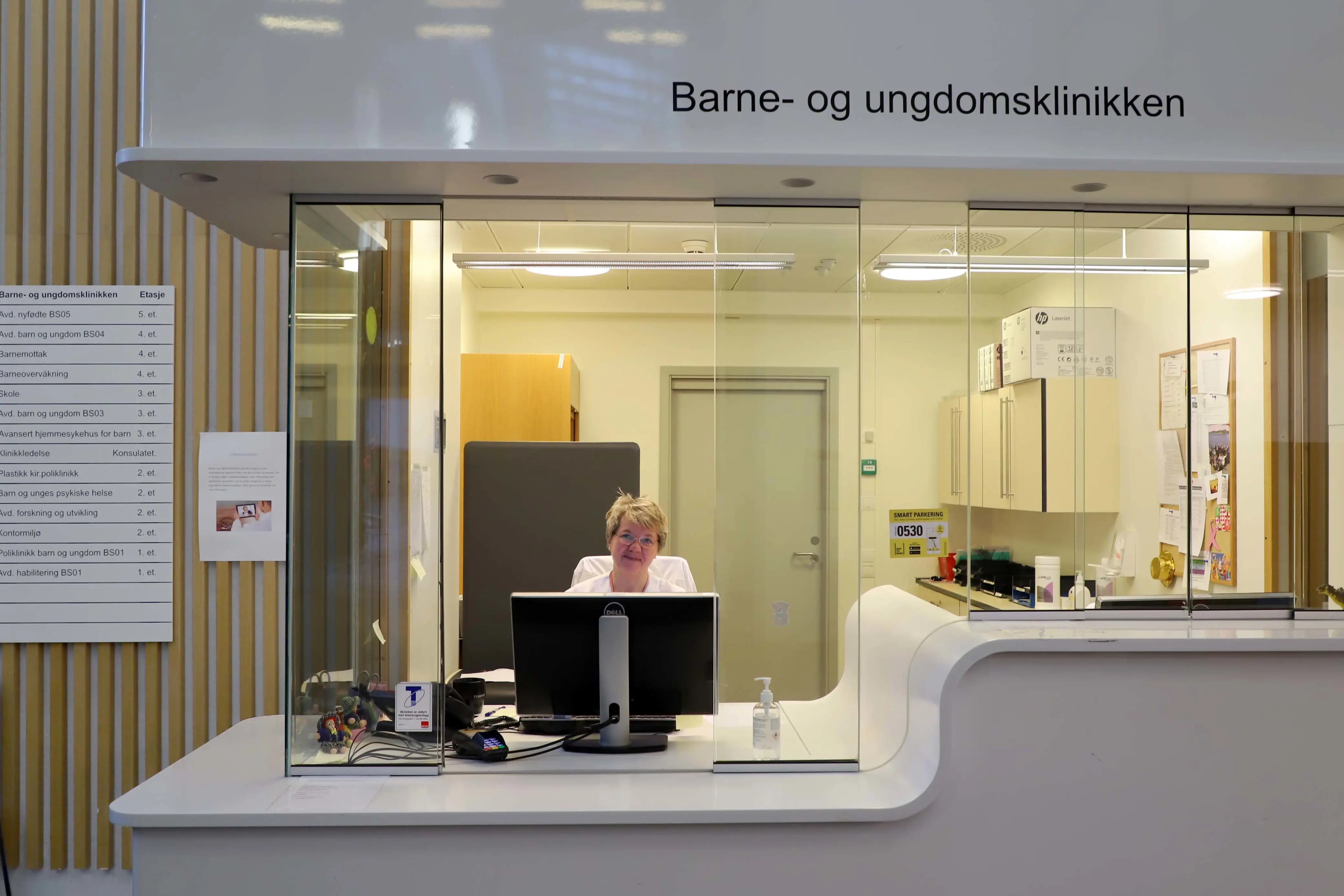 Resepsjonisten på Barne- og ungdomsklinikken smiler bak respesjonen