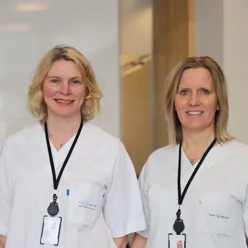 To kvinner med blondt hår og hvite frakker smiler