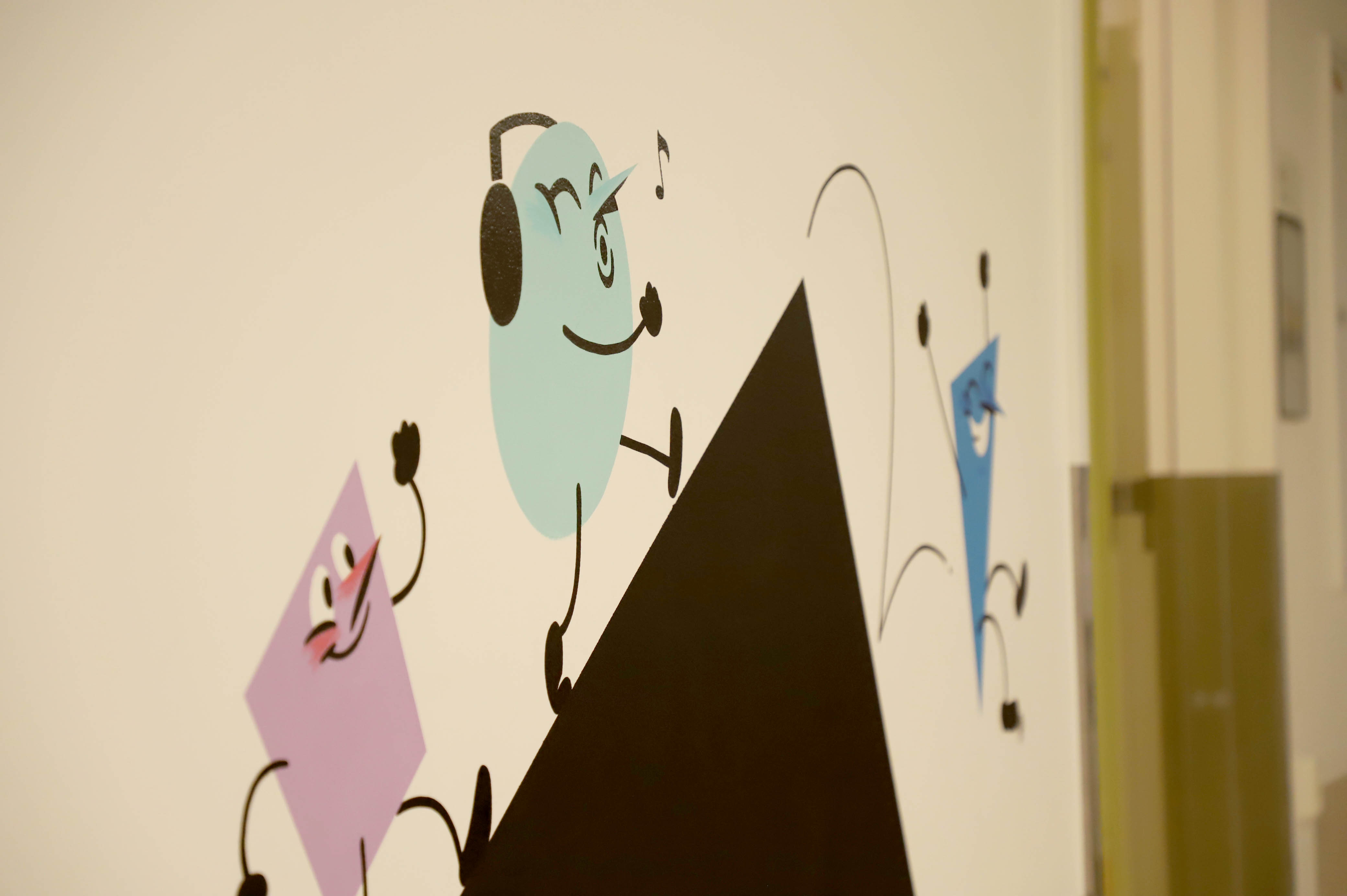 Grafitti på vegg. En blå, runn mann plystrer og hører på musikk.