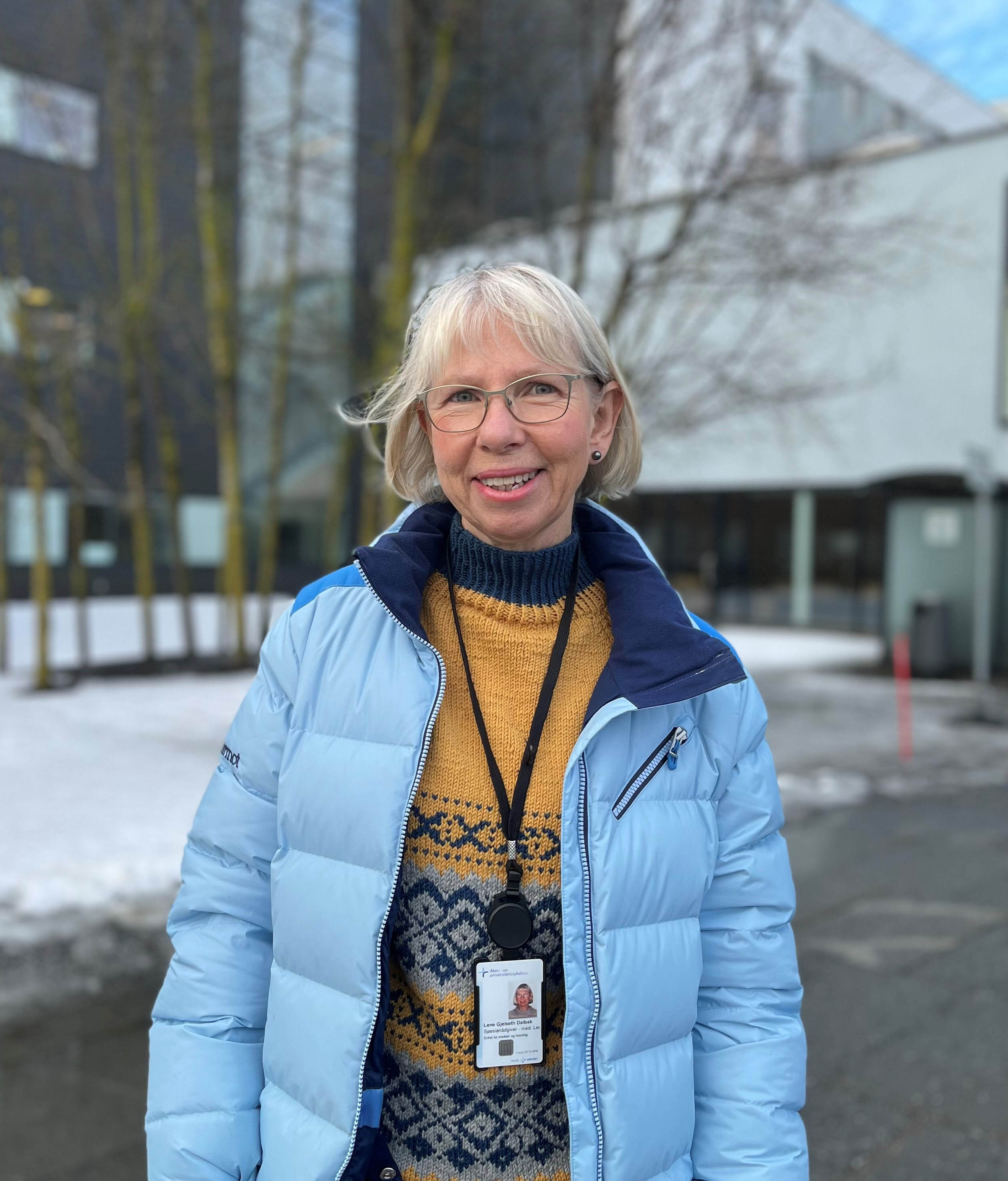 En blond kvinne med kårt hår og blå ytterjakke