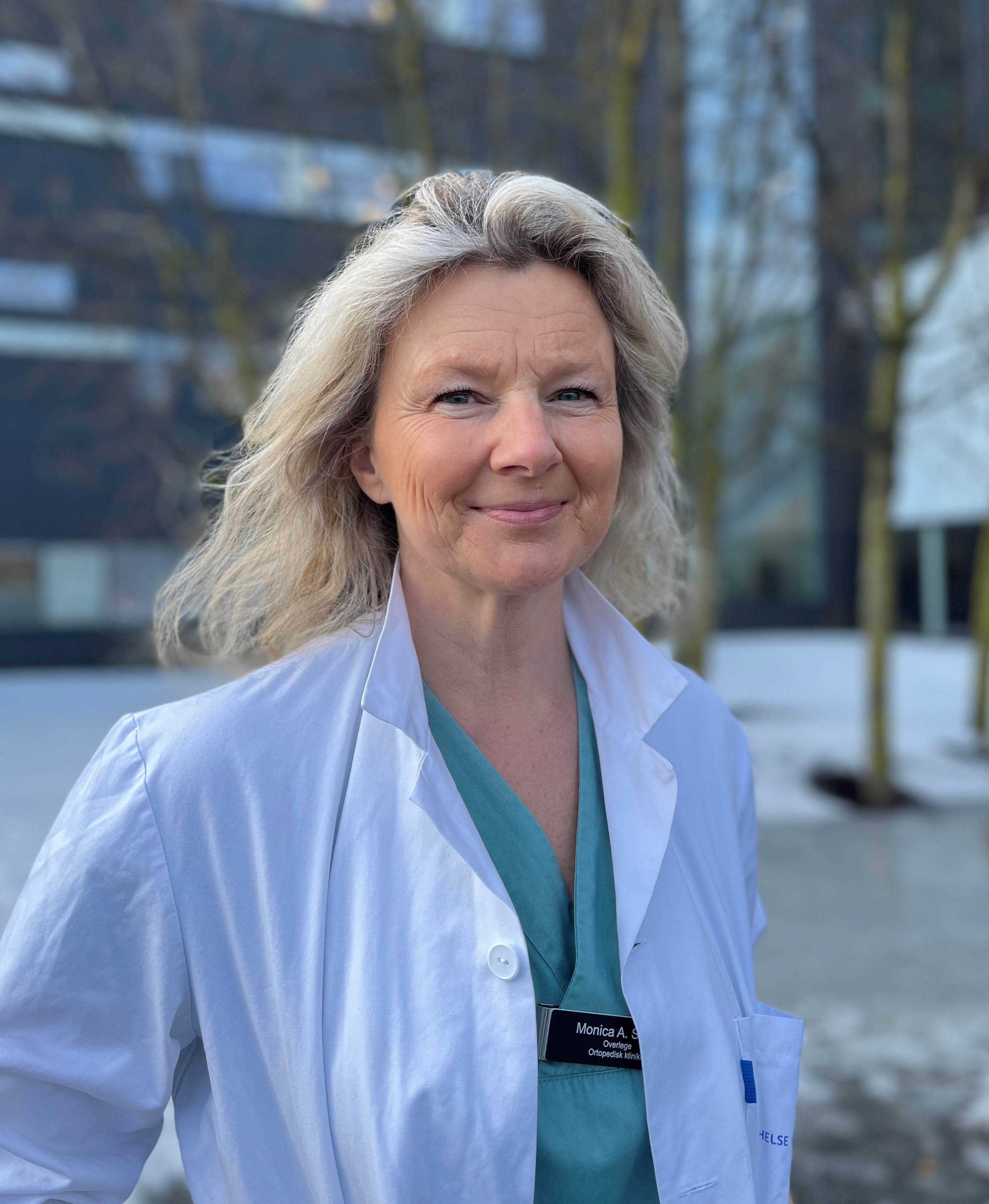 En blond kvinne med langt hår og legefrakk