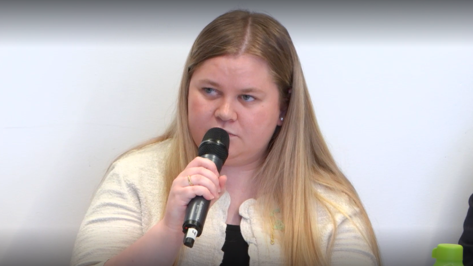 Blond jente med langt hår snakker inn i mikrofon