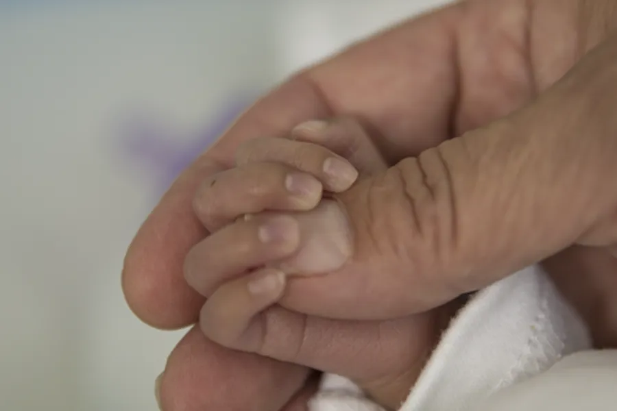 Et nærbilde av en person som holder en babys hånd